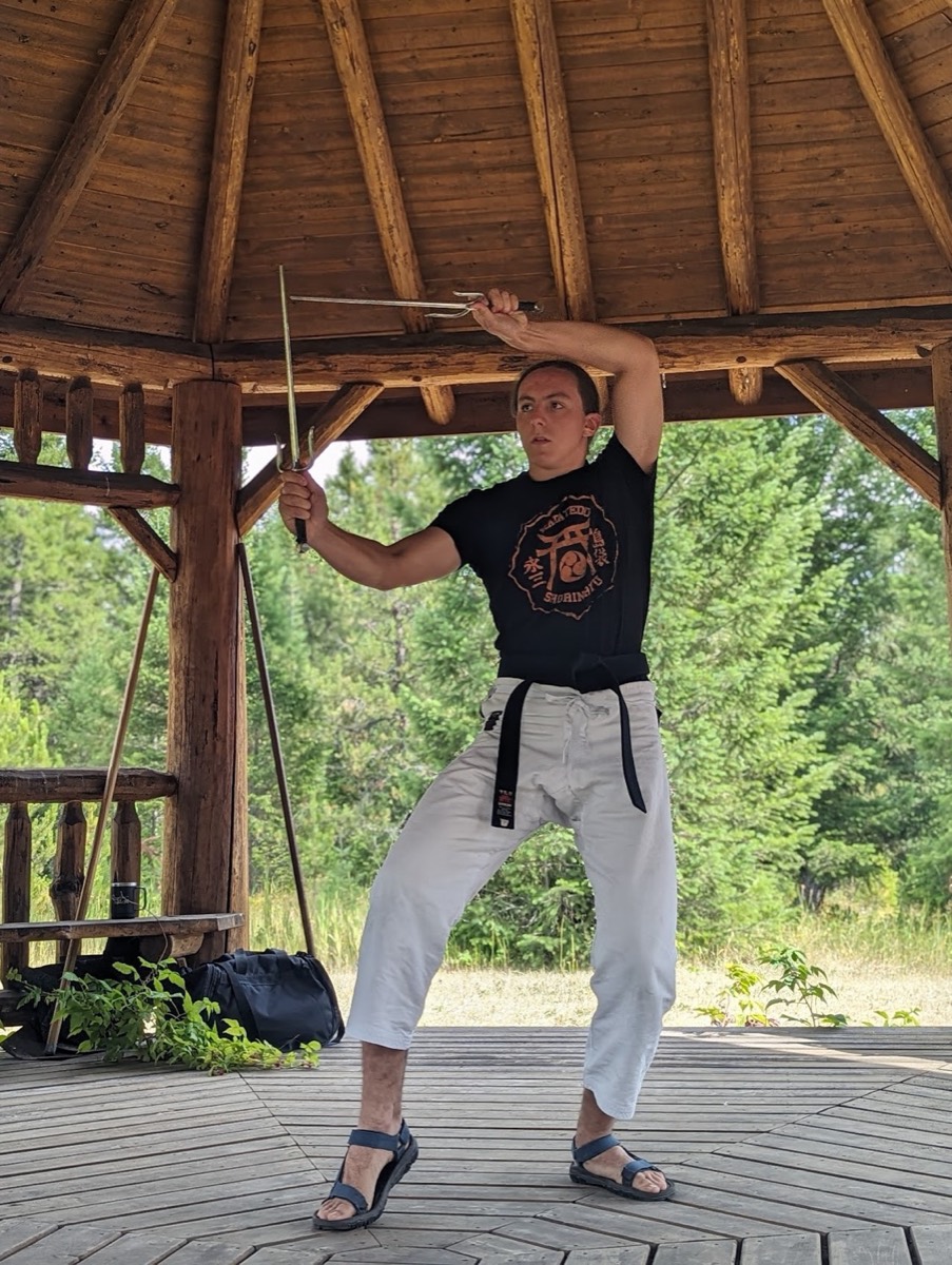 A student practicing bo kata outdoors